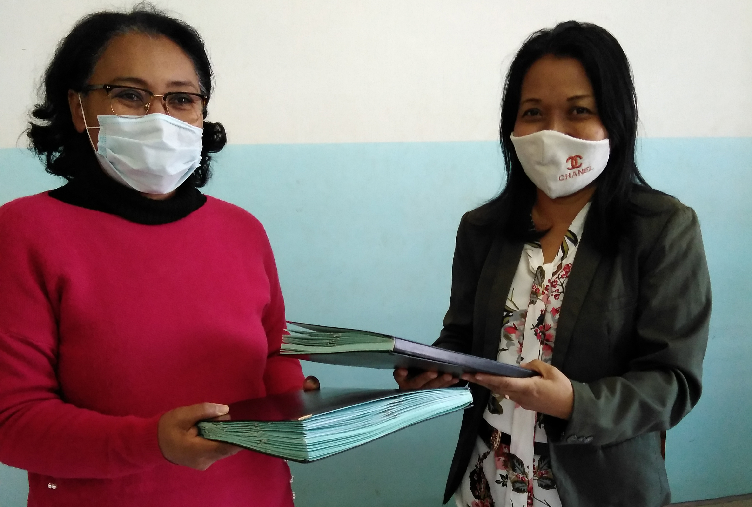 Two women from Madagascar pose in front of a table at a signing ceremony with the School of Medicine, University of Antananarivo.
