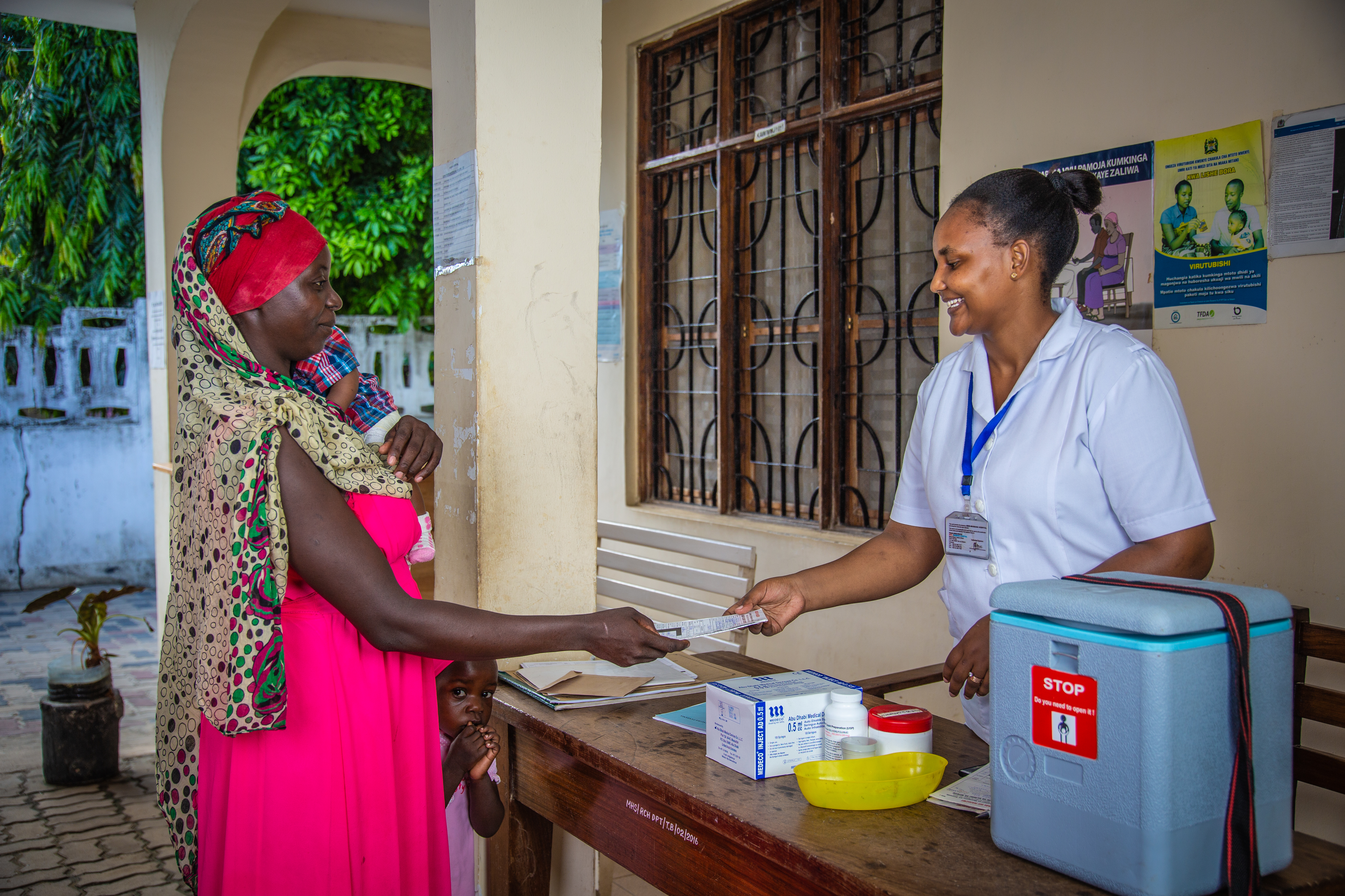 A health worker in Tanzania provides information to a woman holding a baby.