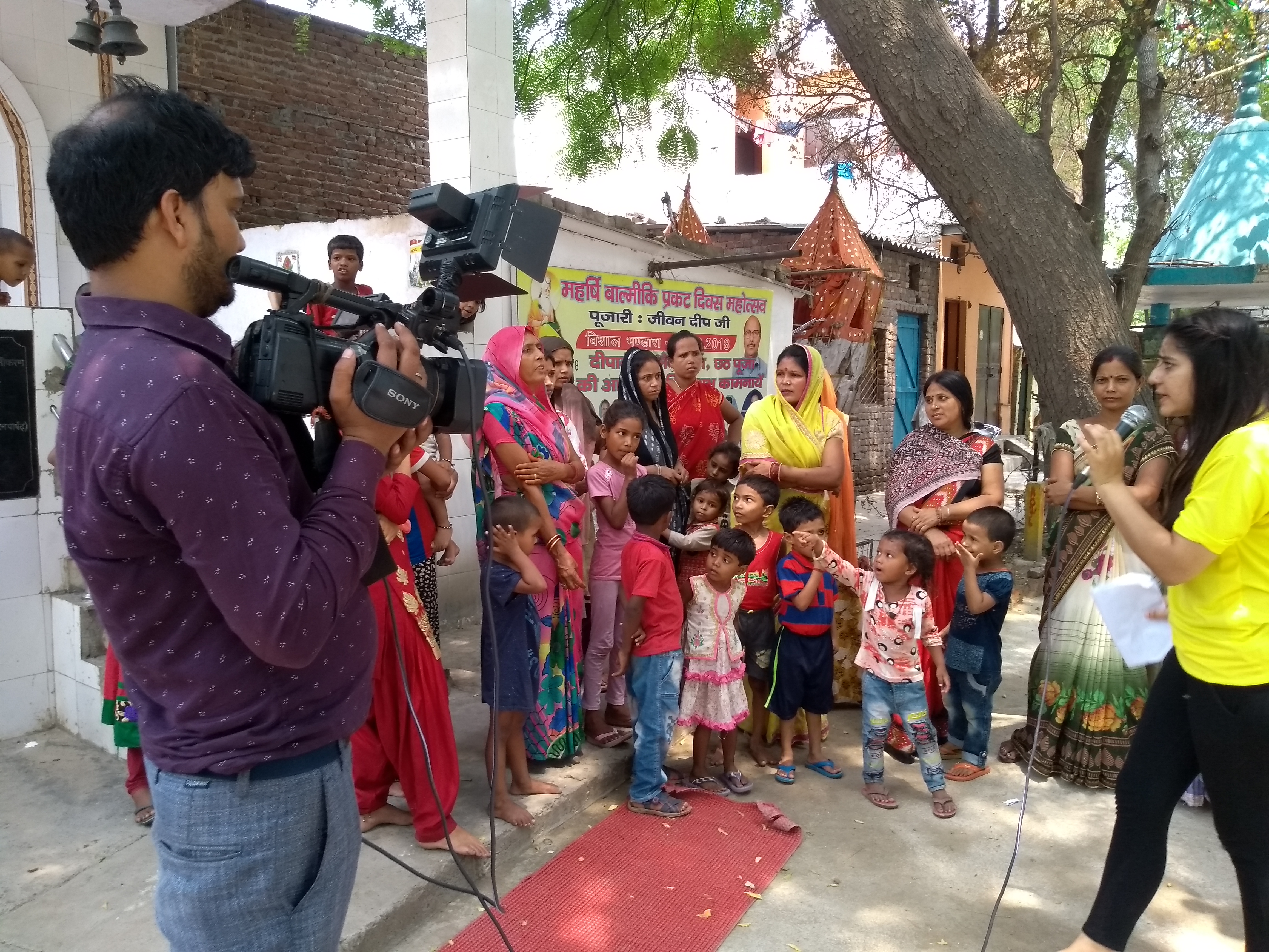 Man with a video camera filming a group of women and children