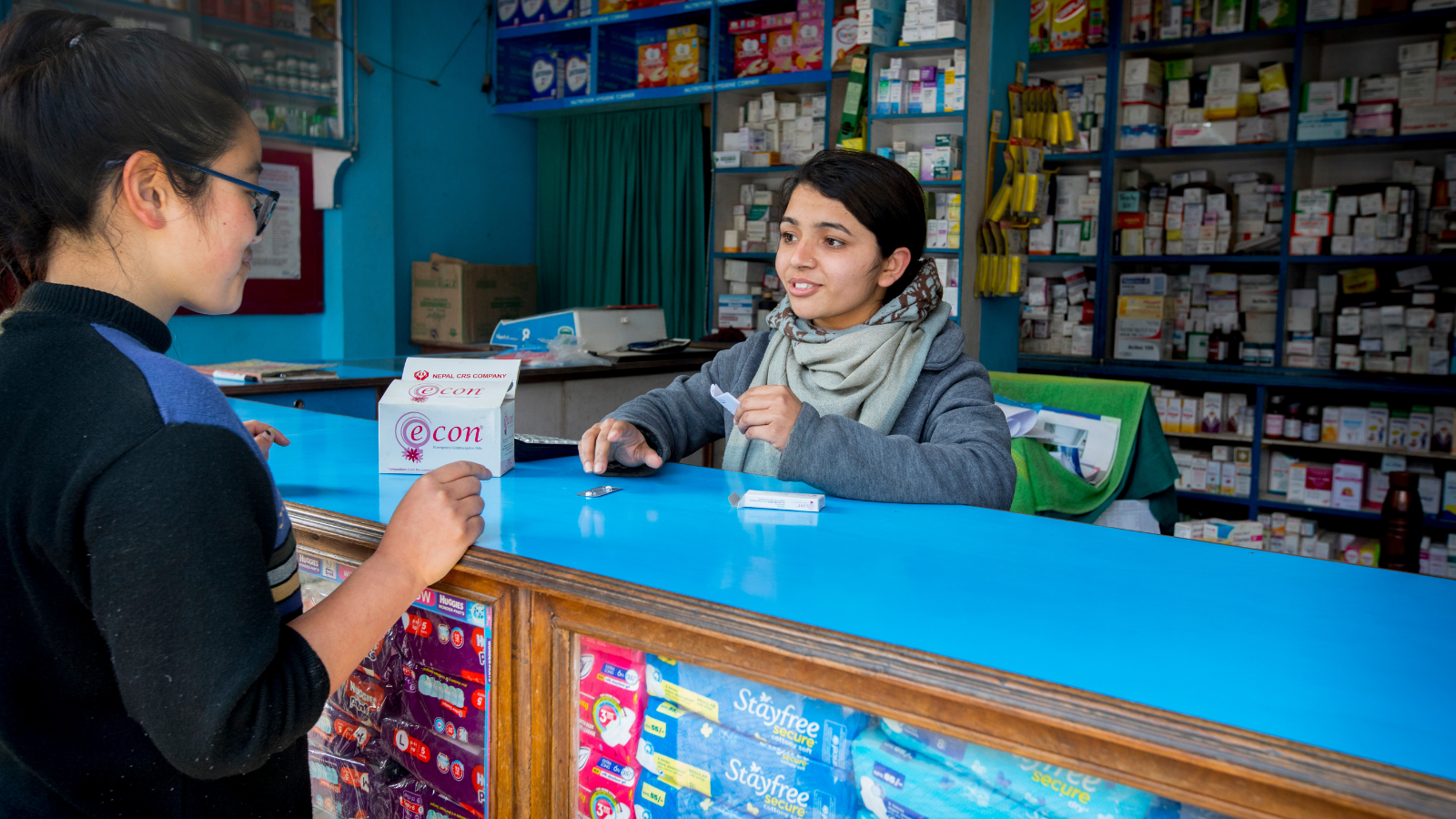 Image of a woman working in a drug shop talking to a client 