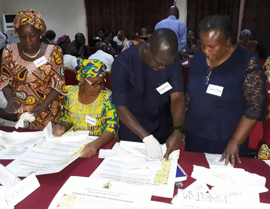 Four participants look through material at a family planning training session in Nigeria