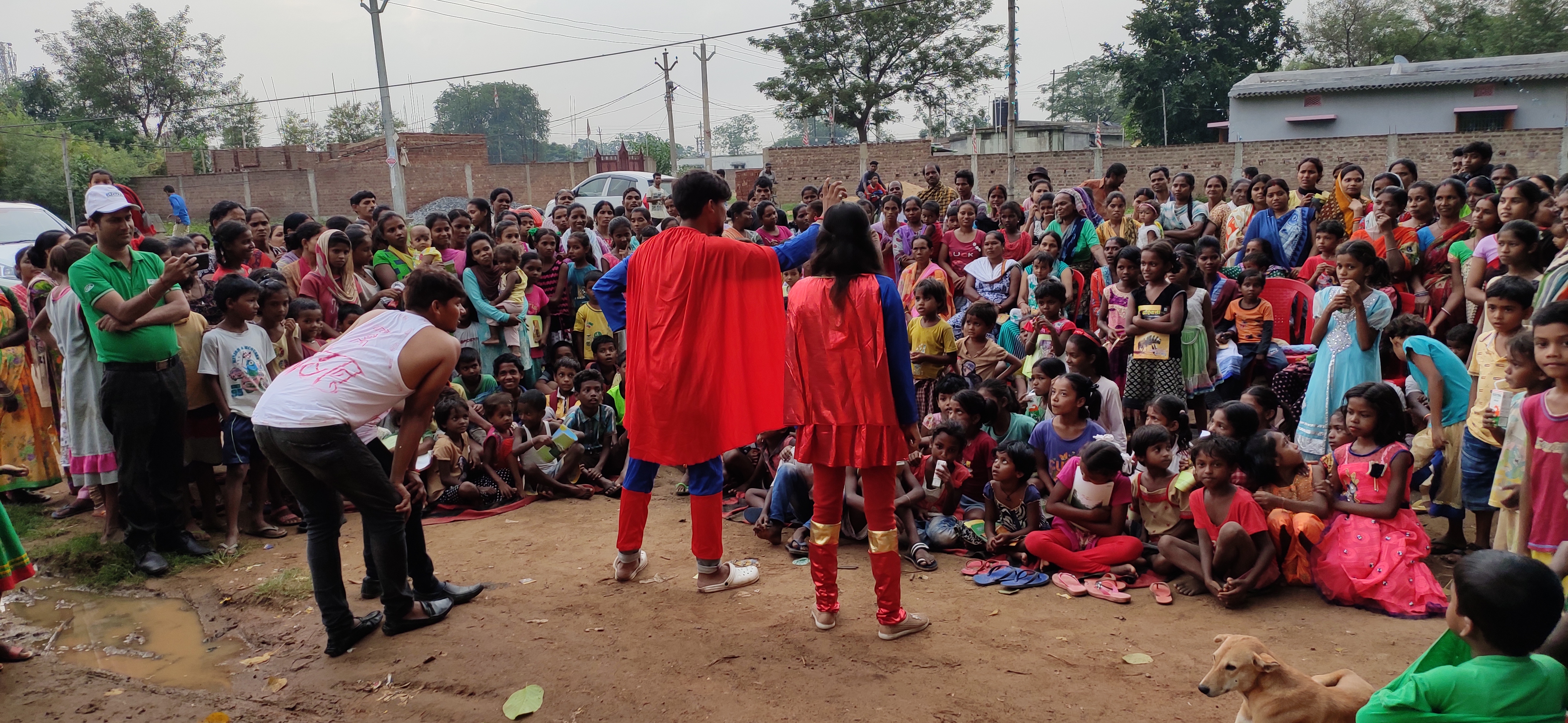 two people dressed as superman and superwoman are talking to a crowed of children and you adults