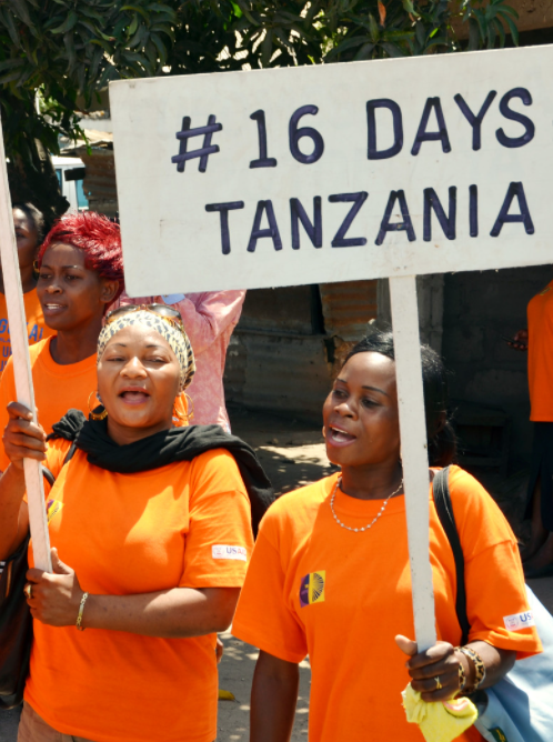Women wearing orange and holding signs that read, #16Days Tanzania. 