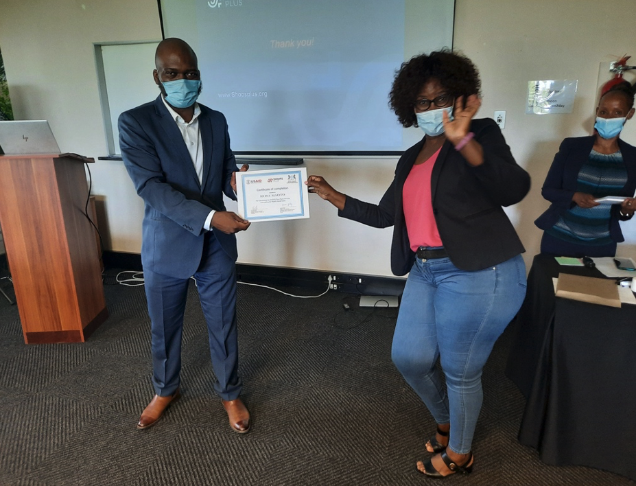 A man and a woman wearing masks and holding a certificate