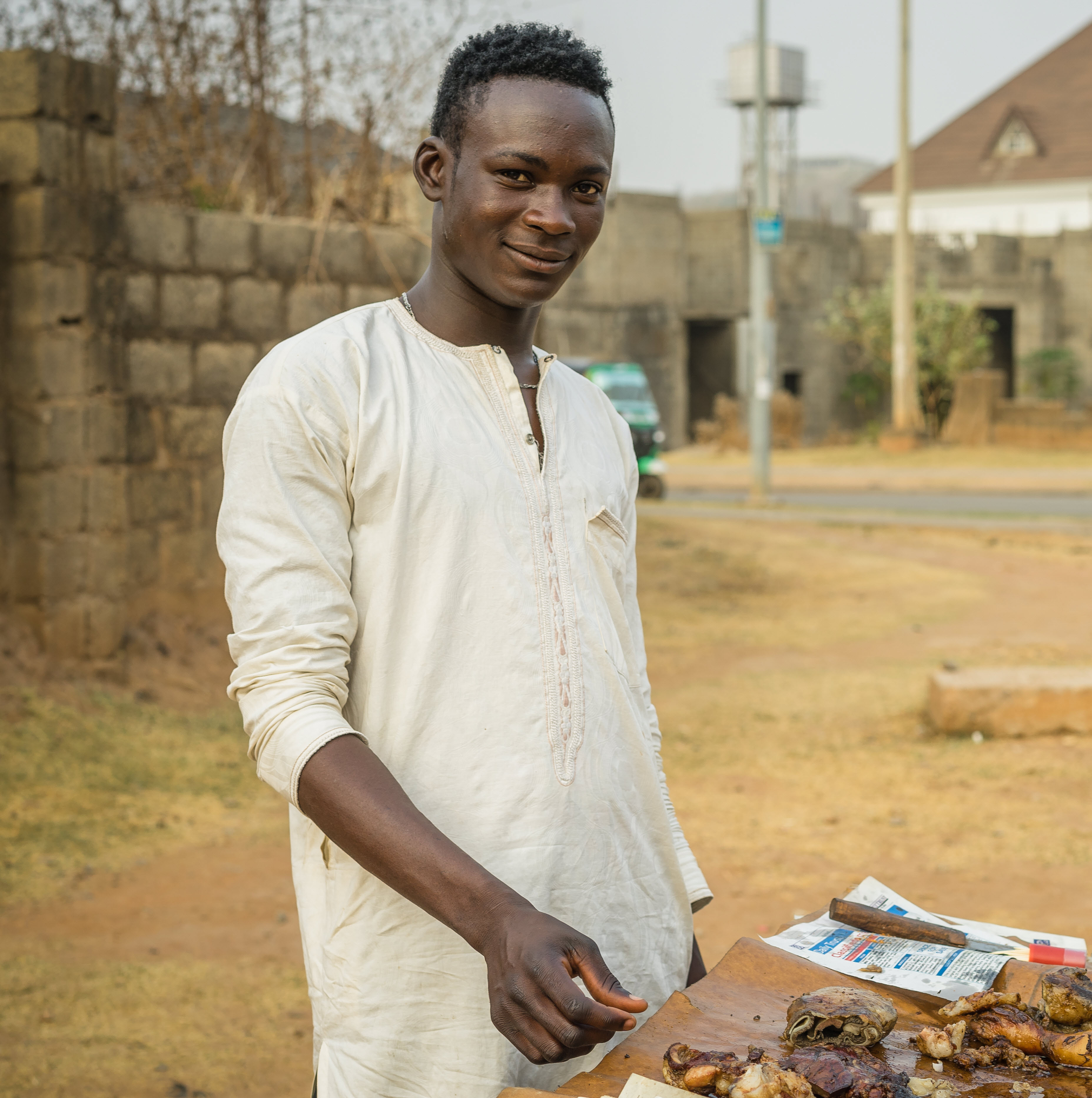 A young Nigerian man sells meat on the street.