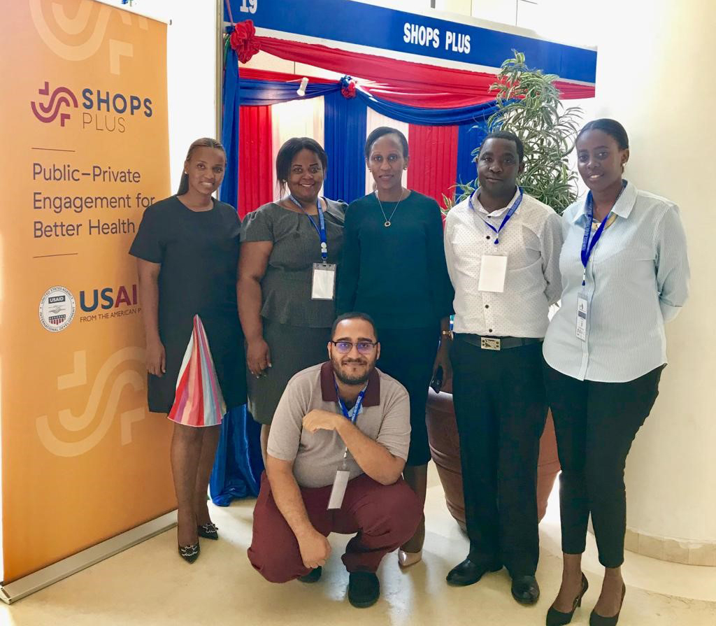 SHOPS Plus team in Tanzania posing for a photo in front of the SHOPS Plus booth at the Tanzania Health Summit