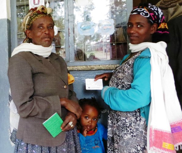 Three generations of women in Ethiopia, with the oldest two holding health insurance cards | Credit: Jeanna Holtz