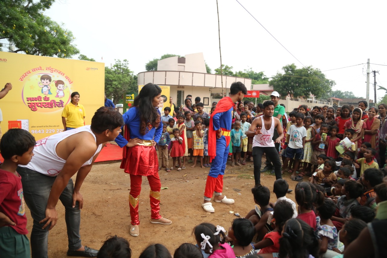 two people dressed as superman and superwoman are talking to a crowed of children and you adults