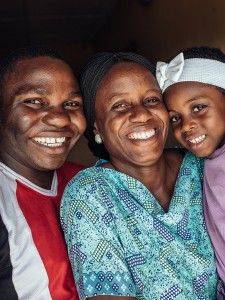 Nigerian, mom, dad, and young daughter posing for a photo. 