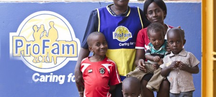A social franchisee stands with a group of children.