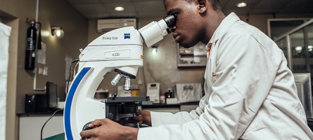 Lab technician looking through a microscope