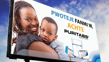 Photo of Puritabs billboard in Haiti with mom and baby next to a clean glass of water. 
