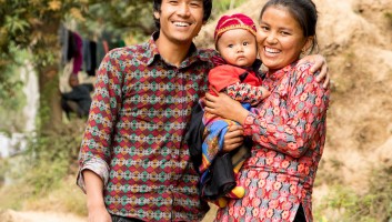 Nepalese mom and dad holding baby and smiling. 