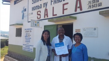 Representatives from SALFA and AccèsBanque Madagascar stand in front of the building holding the certificate of excellence. 