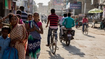 Photo of busy street in India with people walking and riding bikes. 