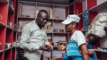 Drug shop owner in Lagos talking to a female client about a product.