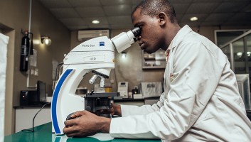 Lab technician looking through a microscope