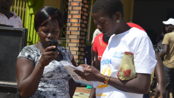 A woman and a community health worker look at a mobile phone