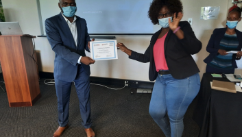 A man and a woman wearing masks and holding a certificate