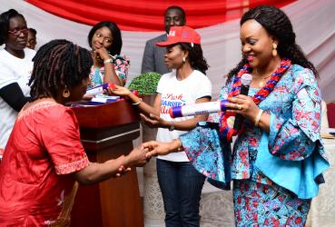 Dr. Eunice Ortom hands a baton to the wife of a local government sole administrator and shakes her hand.